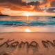 Writing E Komo Mai on the sandy beach at sunset