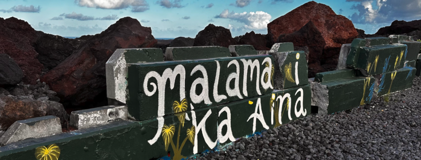 Malama Ka Aina painted on a lava rock wall