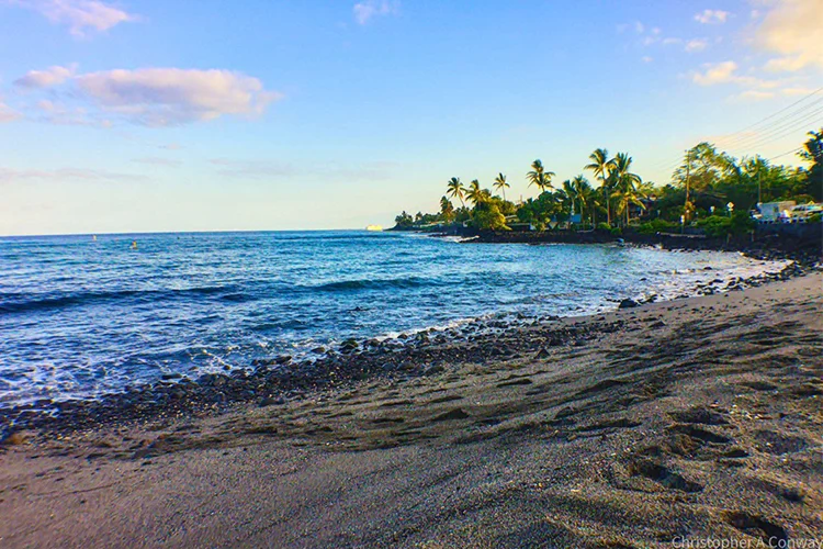 Kahaluʻu Beach Park in Kona, Hawaii at sunset with calm bay and palm trees